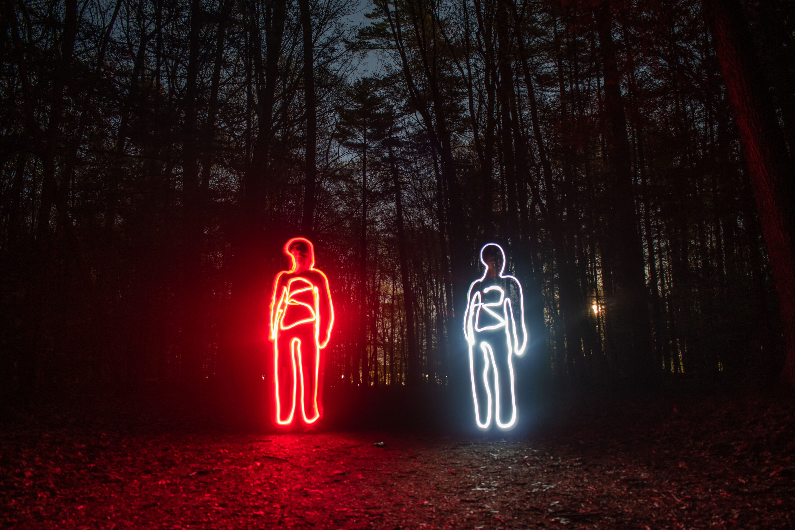 A long exposure photo with two figures drawn in red and white lights.